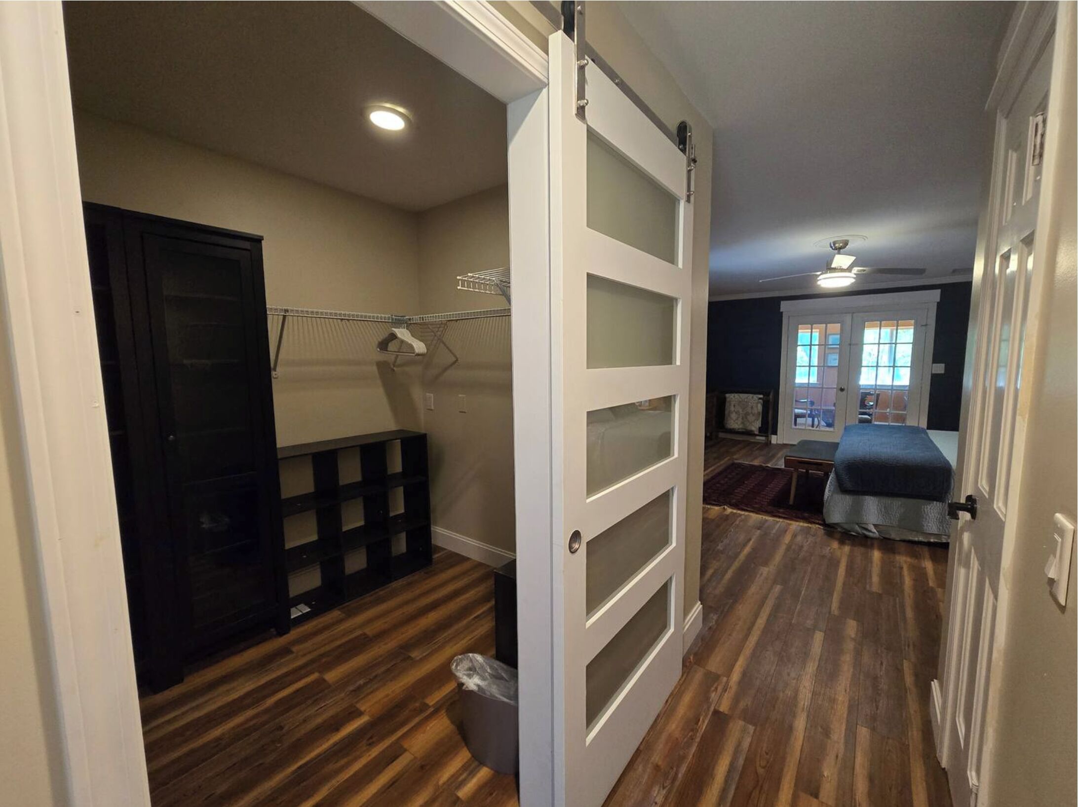 Una habitación con piso de madera, una cama, un armario con puerta corrediza y una ventana con vistas.