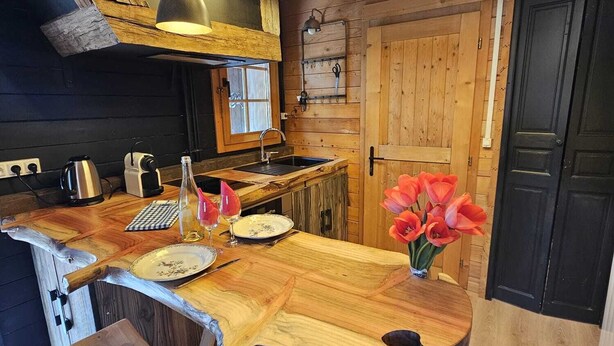 Een landelijke keuken met een houten kookeiland, hanglampen en uitzicht op de woonkamer.