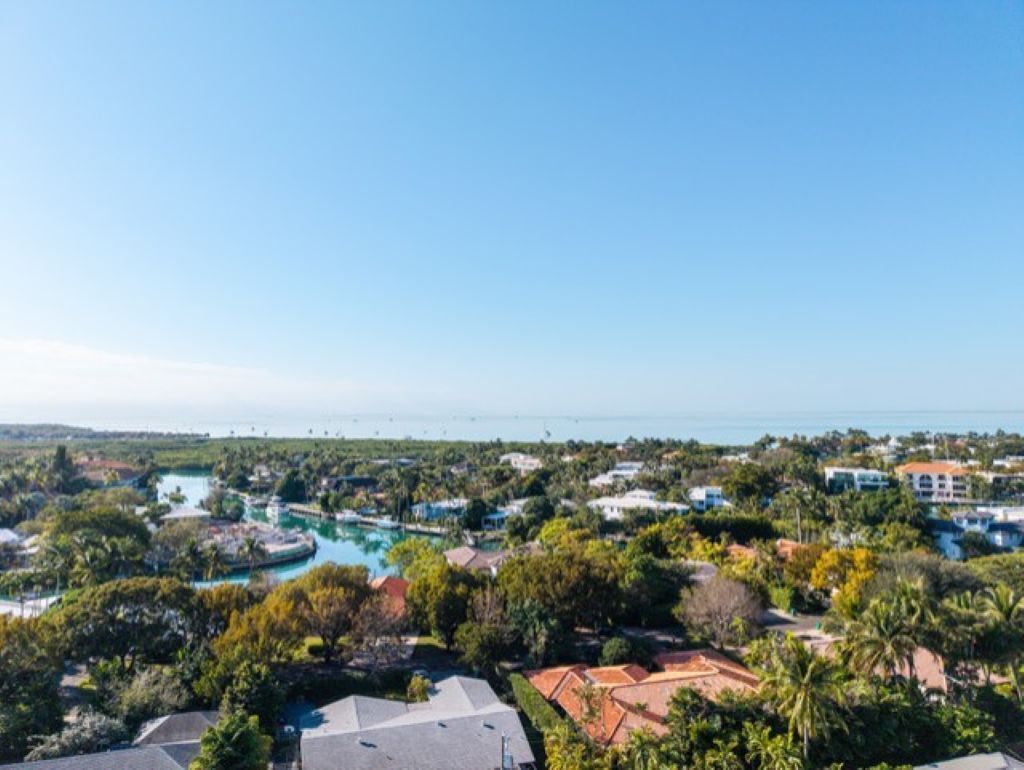 A coastal resort with multiple buildings, a large pool area, and a view of the sea.