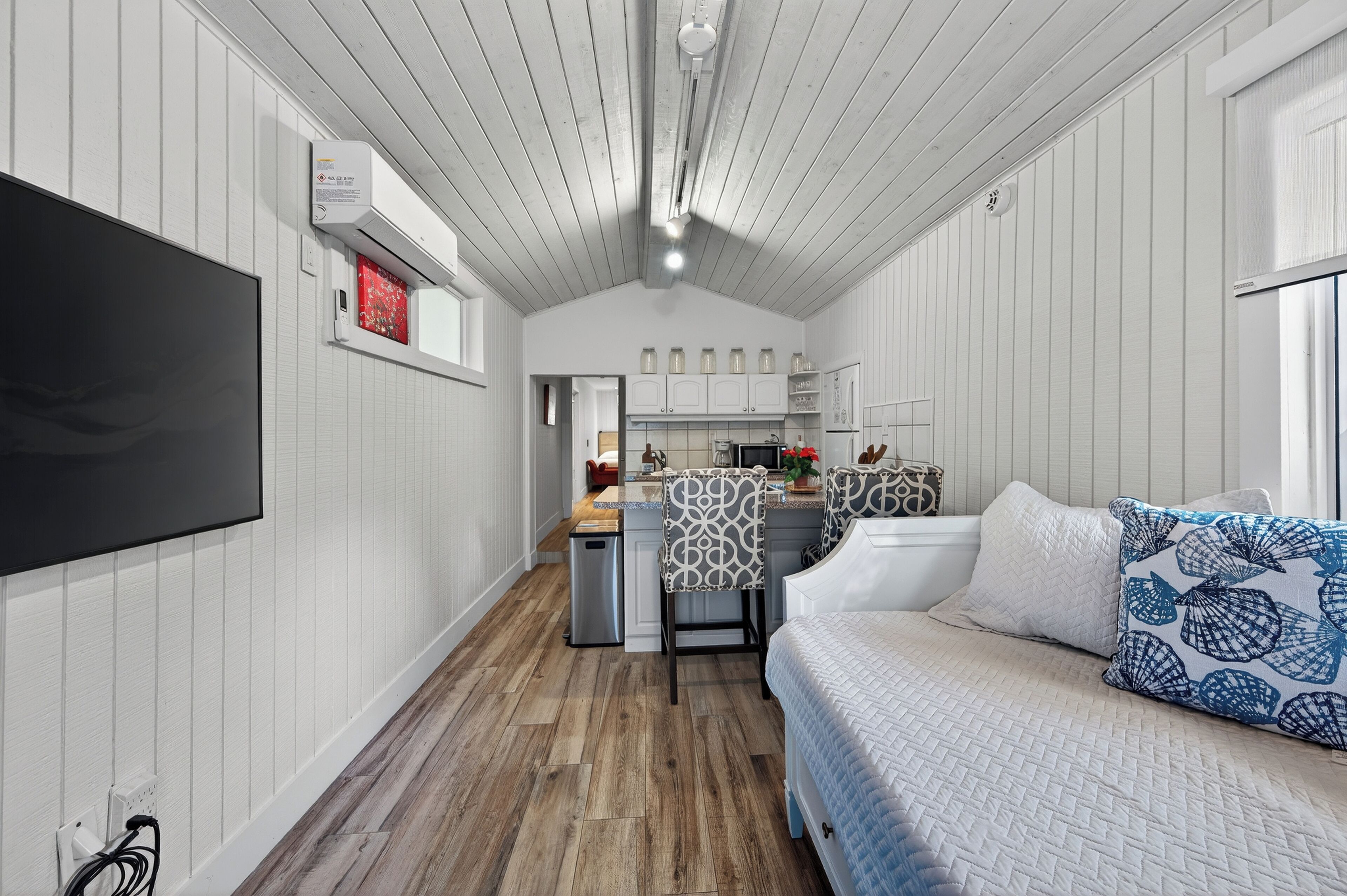 A compact room with a bed, a desk, and a kitchenette.