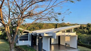 Una casa moderna amb teulada plana, grans finestres i un ampli espai de pati.