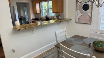 A kitchen with a granite countertop, wooden cabinets, a dining table with placemats, and a chandelier.