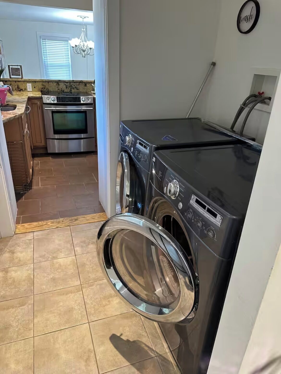 A laundry area with a front-loading washer and dryer, a kitchen with a built-in oven, and a chandelier.