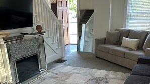 A living room with a fireplace, a sofa, and a television. -  Cozy Cape Cod in lovely Allentown with modern amenities (Allentown)