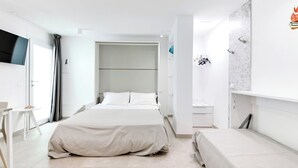 A modern hotel room with a large bed, a desk, and a TV.