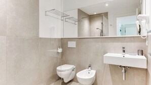 A modern bathroom with a toilet, bidet, and sink.