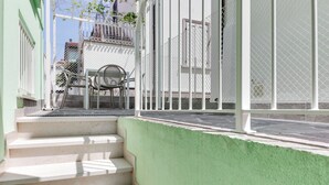 A staircase leading to a green-painted building with a white fence and a chair outside.