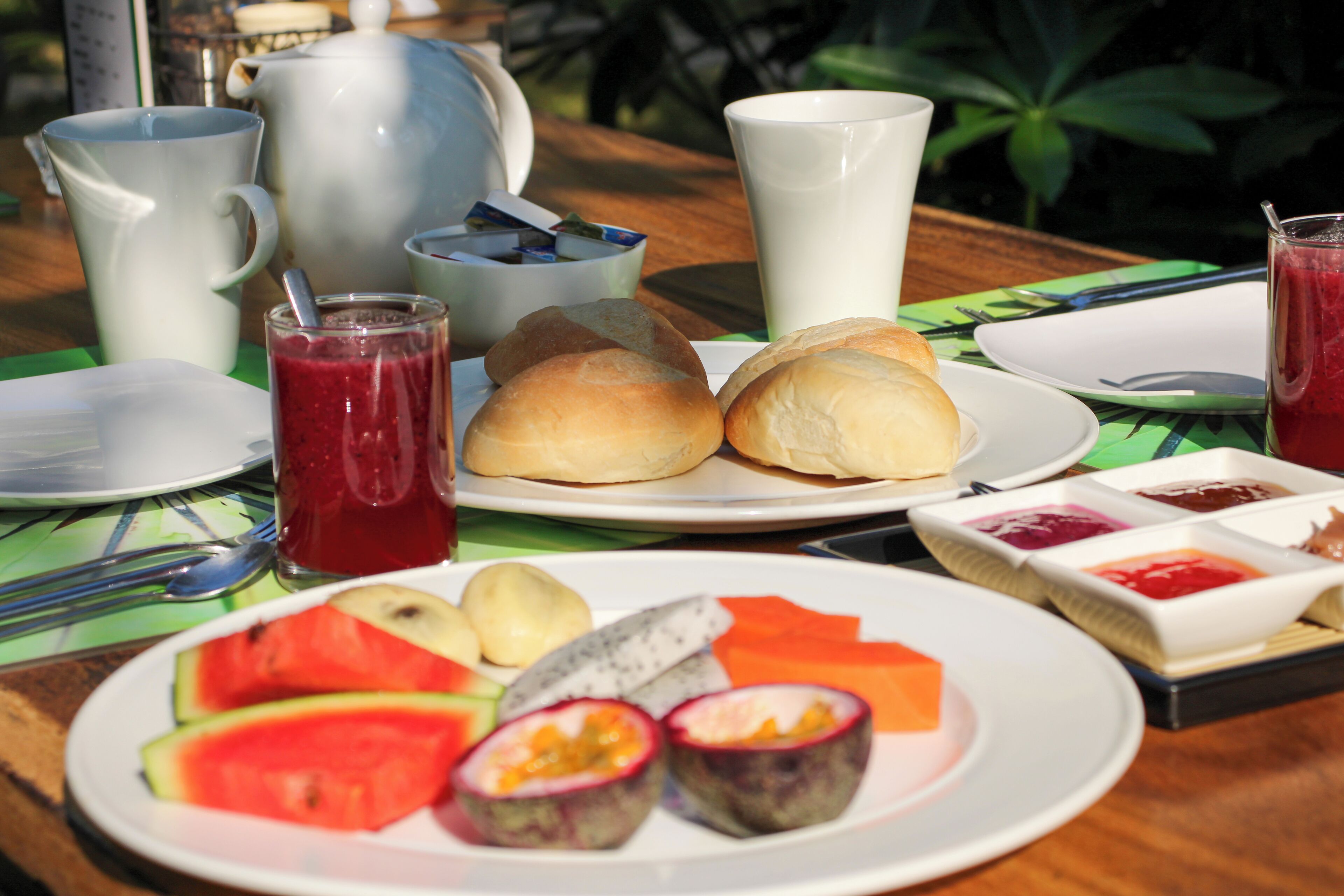 A table set with breakfast items including bread, fruit, and beverages.