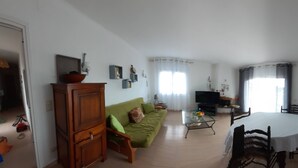 Un salon comprenant un canapé, un téléviseur, une table à manger et un meuble.