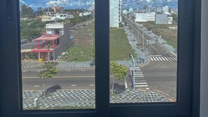 A view through a window with a clear sky and buildings in the distance. - Luna Hotel Phan Thiet (Phu Thuy)