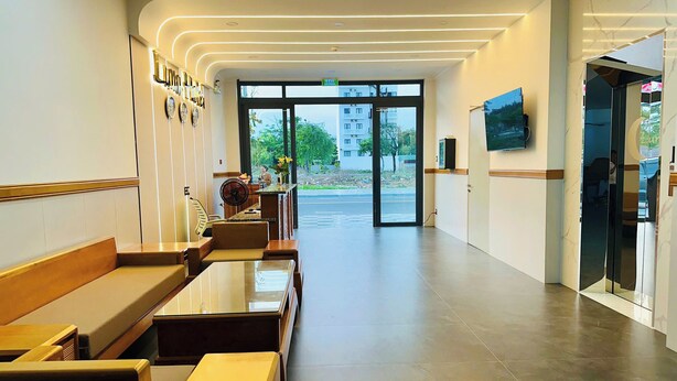A modern lobby with seating areas, a reception desk, and a large window offering a view of the outside. - Luna Hotel Phan Thiet (Phu Thuy)