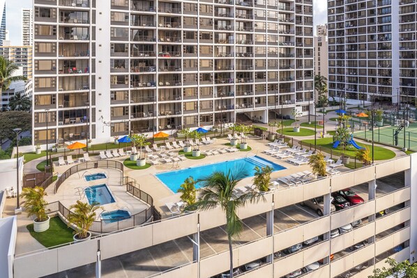 A multi-story hotel with a rooftop pool area, including sun loungers and a hot tub.