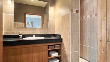 A modern bathroom with a wooden vanity, a sink, and a mirror.