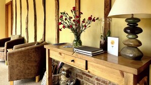 Un bureau en bois orné d’un vase de fleurs rouges, d’une lampe et d’un tableau encadré.
