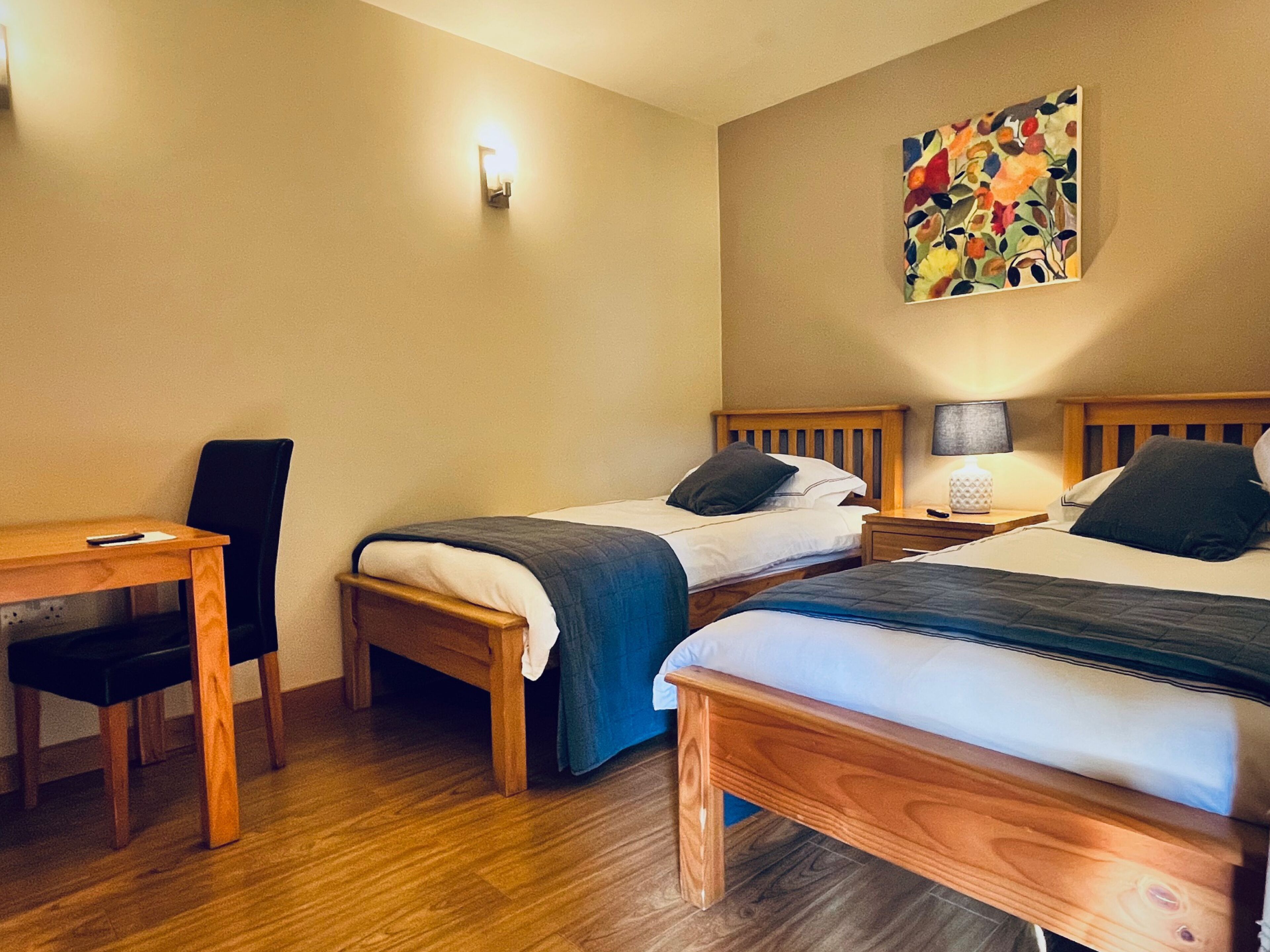 A hotel room with two wooden beds, a desk, and a chair.
