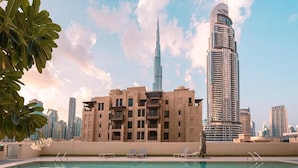 Ein Swimmingpool mit Liegestühlen, ein Gebäude mit modernem Design und der Burj Khalifa im Hintergrund.