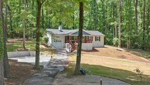 A house surrounded by trees with a covered porch and a staircase leading to the entrance. - Forest Retreat: Cozy Getaway (Wake Forest)