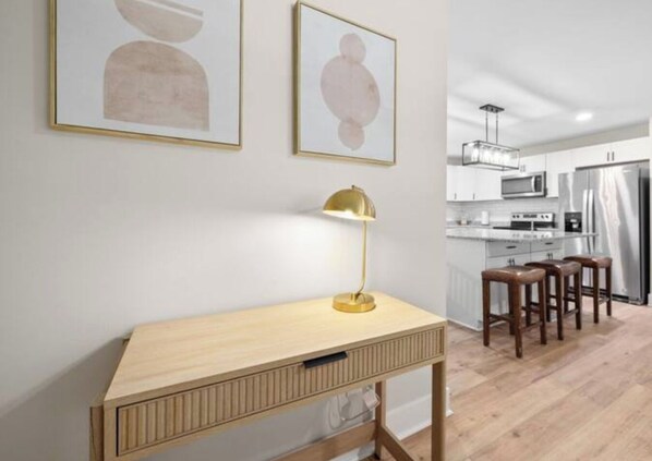 A modern kitchen with white cabinets, stainless steel appliances, and a wooden dining area with stools. - Forest Retreat: Cozy Getaway (Wake Forest)