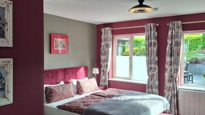 A bedroom with a bed, a headboard, a window with curtains, and a wall with framed pictures. - Quaint studio in Galway, Clarinbridge for a peaceful getaway (Galway, Clarinbridge)