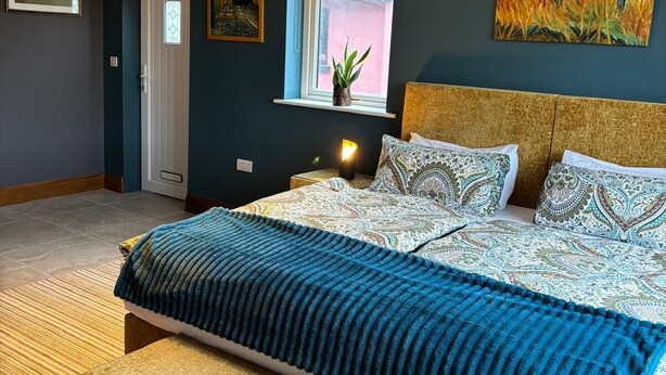 A bedroom with a bed, a nightstand, a window, and artwork on the walls. - Bed & Breakfast, Stoneywood Haven in Galway, Clarinbridge (Galway, Clarinbridge)