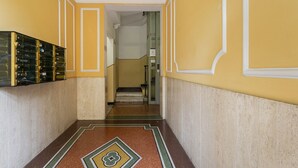 A hallway with yellow walls, a patterned floor, and a staircase leading to another room. - Happy Family Apartment by Wonderful Italy (Genoa)