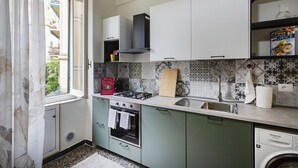 A compact kitchen with a gas stove, oven, and washing machine. - Happy Family Apartment by Wonderful Italy (Genoa)