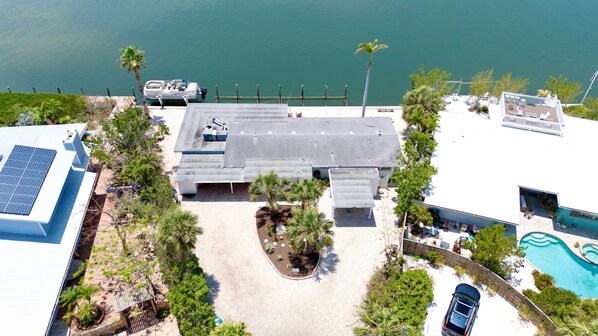 An aerial view of a coastal property with a large building, a swimming pool, and a boat dock.