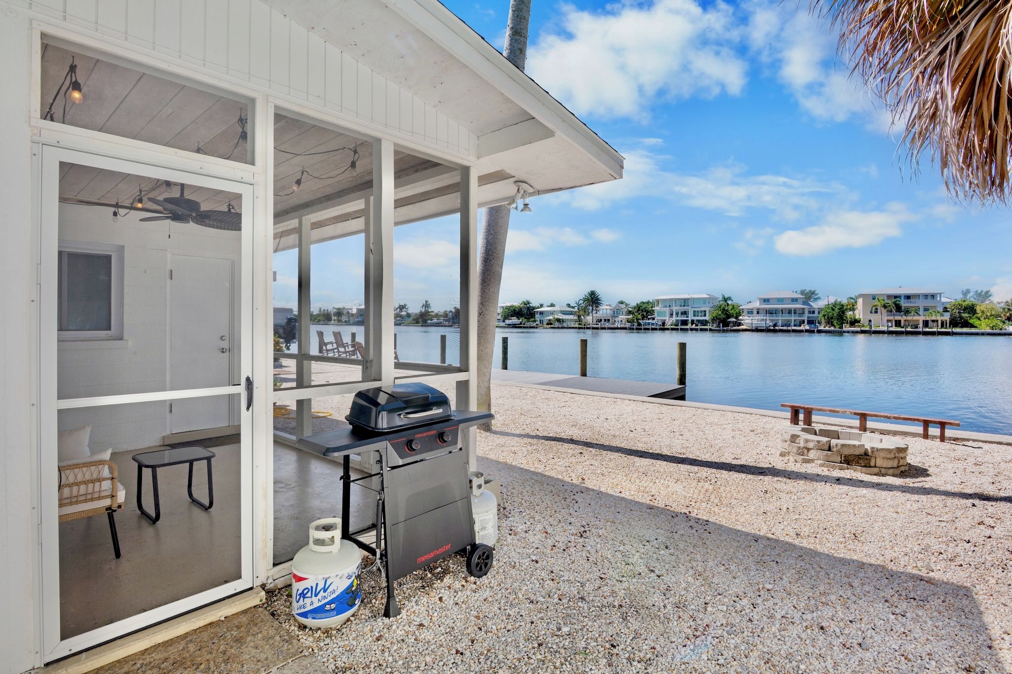 Ein überdachter Grillbereich mit Blick auf einen Wasserweg und Gebäude im Hintergrund.