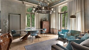 A spacious room with a large round table, blue upholstered chairs, a wooden cabinet, and a chandelier. - Castelpoggio Luxury Apartment (Ponte di legno)