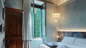 A bedroom with a large window, a chandelier, and a wooden wardrobe. - Castelpoggio Luxury Apartment (Ponte di legno)