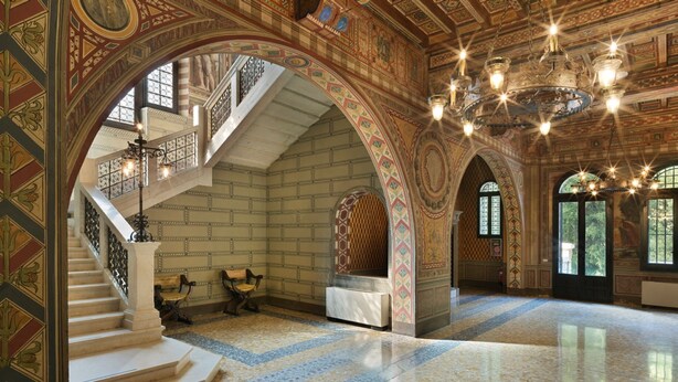 A grand interior with a marble staircase, ornate arches, and a chandelier. - Castelpoggio Luxury Apartment (Ponte di legno)