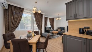 Una sala moderna con comedor, armarios grises y una cocina con hervidor y tostadora.