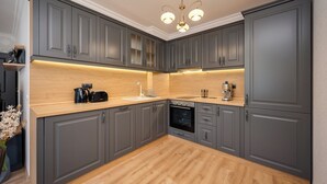 Una cocina moderna con armarios grises, encimera de madera y horno empotrado.