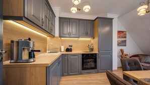 A modern kitchen with grey cabinets, a built-in oven, and a coffee machine. - Prestige Central Apartment 10 (Varna)