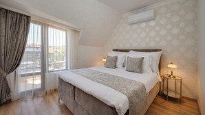 A bedroom with a large bed, a window with curtains, an air conditioning unit, and a bedside lamp. - Prestige Central Apartment 10 (Varna)