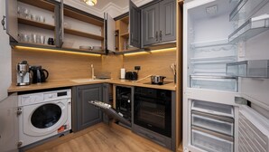 A compact kitchen with a washing machine, oven, and built-in refrigerator. - Prestige Central Apartment 10 (Varna)