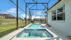 Ein Schwimmbad mit Glasveranda, Whirlpool und Blick auf eine Wohngegend.