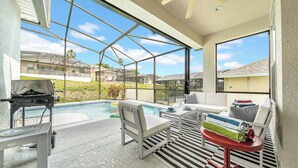 Ein überdachter Außenbereich mit Pool, Sitzgelegenheiten und Grill.