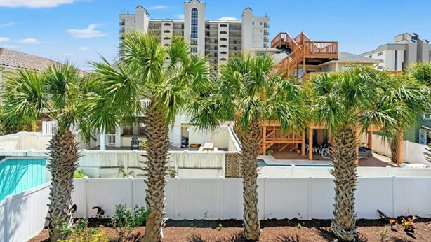 Un resort con piscina, palmeras y un edificio con varios balcones.