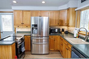 A kitchen with wooden cabinets, stainless steel appliances, granite countertops, and a built-in oven.