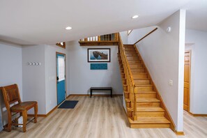 A staircase with wooden steps and a handrail, a bench, a door with a blue frame, and a wall-mounted picture. - Private Home in Egg Harbor-Sleeps 13 with Fire pit (Egg Harbor)
