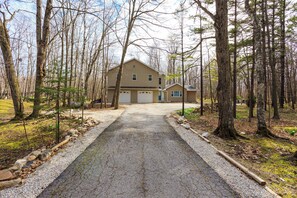 A two-story house with a driveway leading to a garage, surrounded by trees. - Private Home in Egg Harbor-Sleeps 13 with Fire pit (Egg Harbor)
