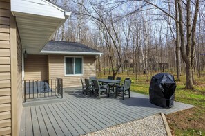 Una terrazza con tavolo e sedie, un barbecue coperto e una casa con una finestra.