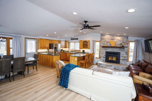 A spacious living area with a fireplace, a dining area, and a kitchen.