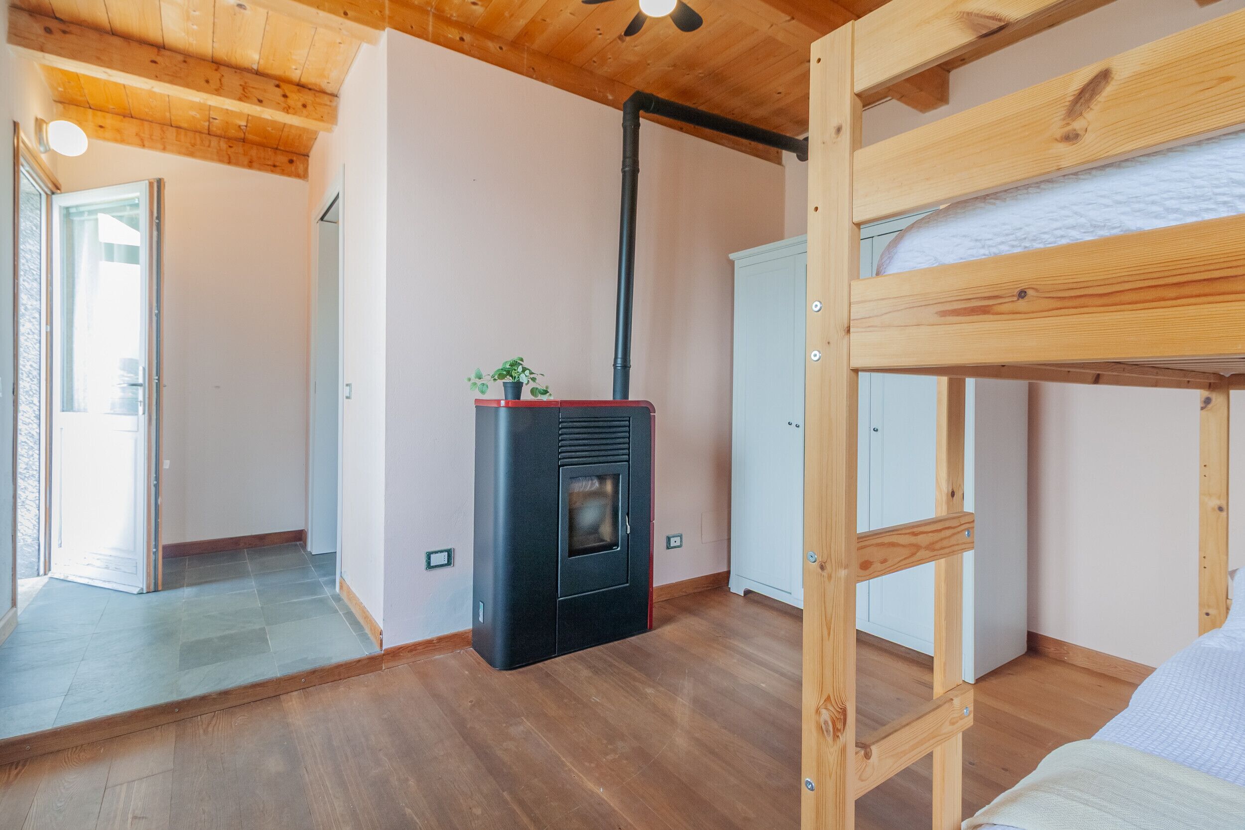 Une pièce avec un lit superposé, une cheminée et une porte donnant sur une autre pièce.