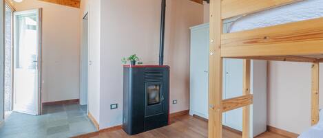 Une pièce avec un lit superposé, une cheminée et une porte donnant sur une autre pièce.