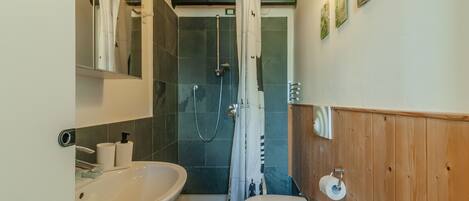 A bathroom with a shower, toilet, and sink.