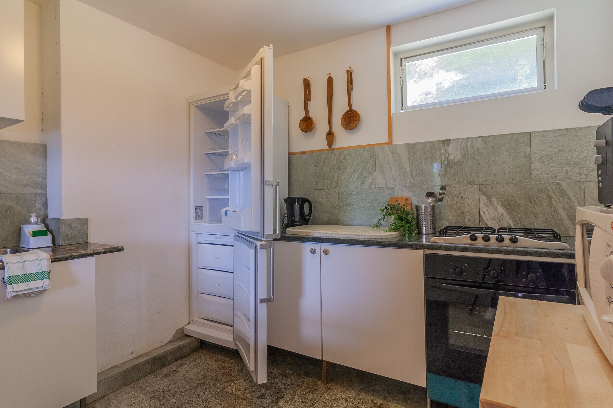 A compact kitchen with a built-in oven, a gas stove, and a refrigerator.