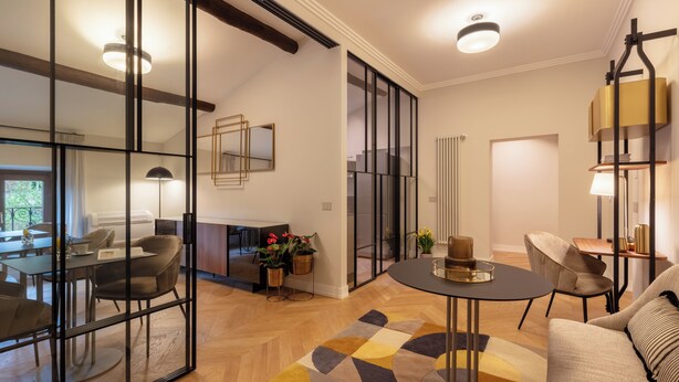 A modern living room with a sofa, a coffee table, and a dining area with chairs and a table. - Decòncept House (Rome)