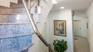 A staircase with a metal handrail and a potted plant at the bottom. - Alnes Hotel (Sarande)